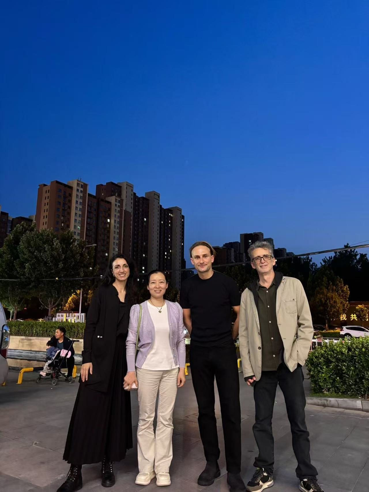 Hosts and visitors on a city square at dusk
